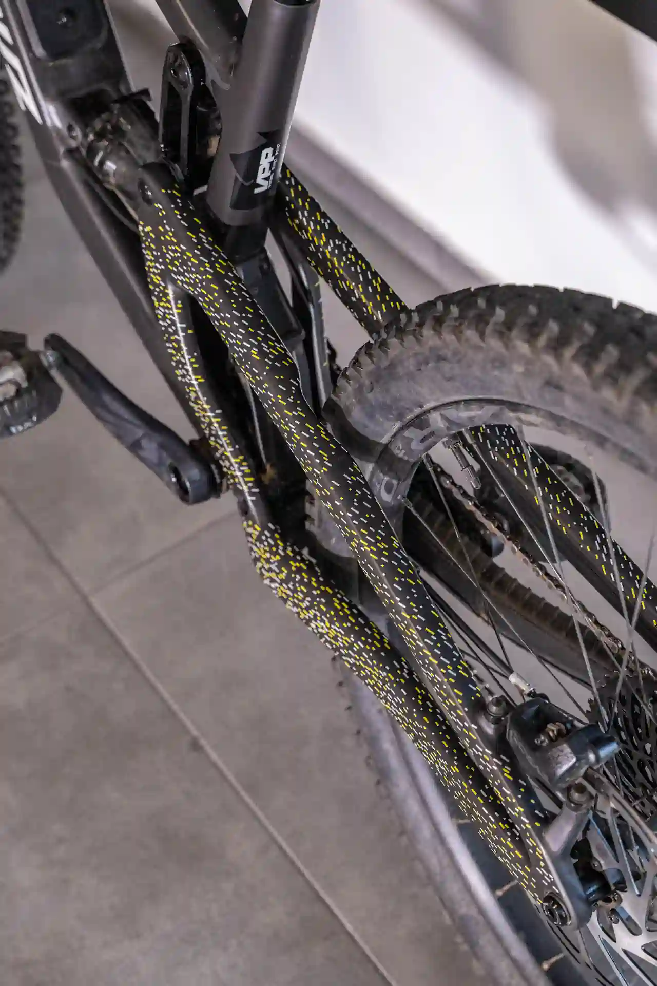 Tylna część roweru z widocznymi żółtymi i białymi wzorami folii ochronnej na wahaczu