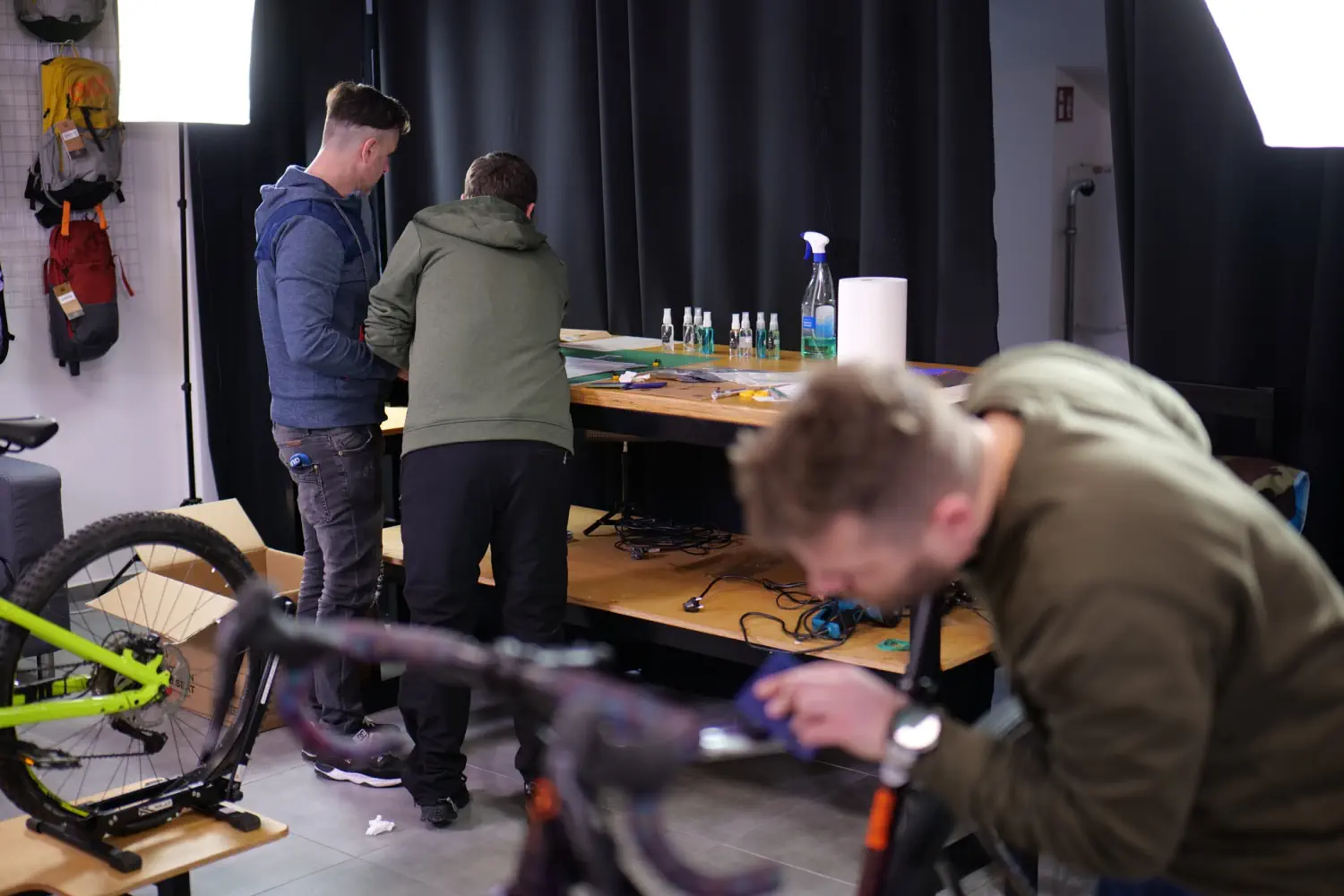 Mężczyźni pracują nad rowerem w warsztacie, na stole folie ochronne