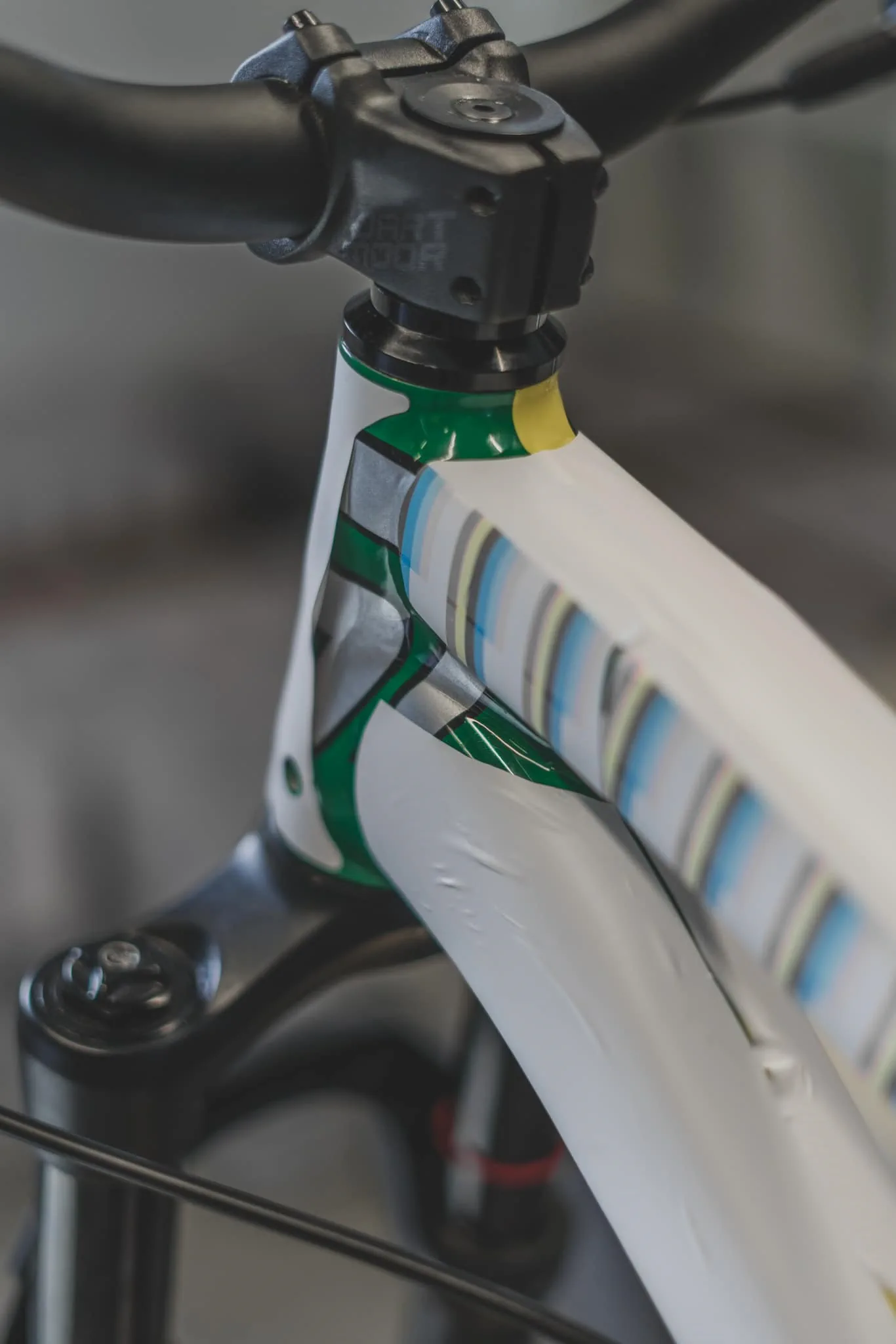 Zielono-żółty rower z widoczną amortyzacją i podczas przygotowań do oklejania, stojący w warsztacie