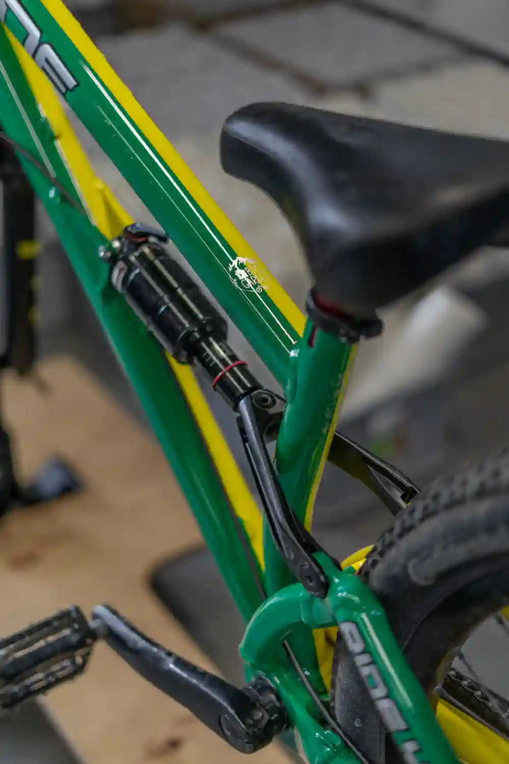 Szczegółowy widok na żółto-zieloną ramę roweru z grafiką i osprzętem