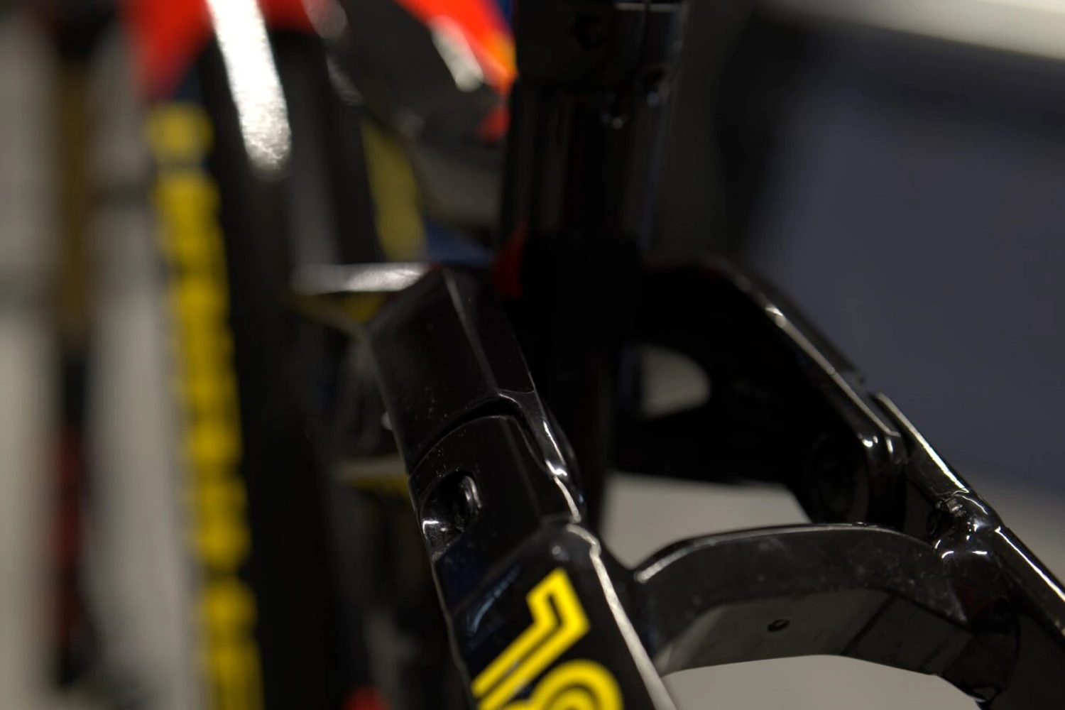 Zbliżenie na przednią część ramy roweru z czerwono-czarną folią ochronną i złotymi elementami zawieszenia
