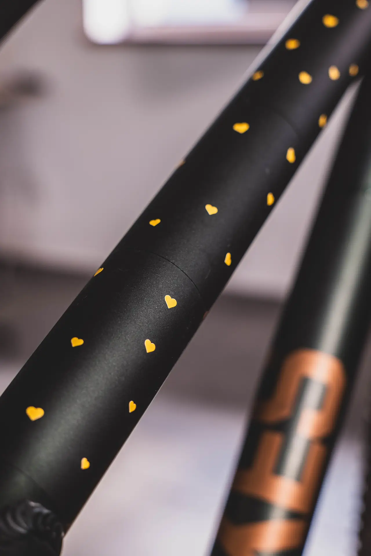Szczegółowa fotografia rury roweru oklejonej folią ochronną z żółtymi serduszkami na matowym tle