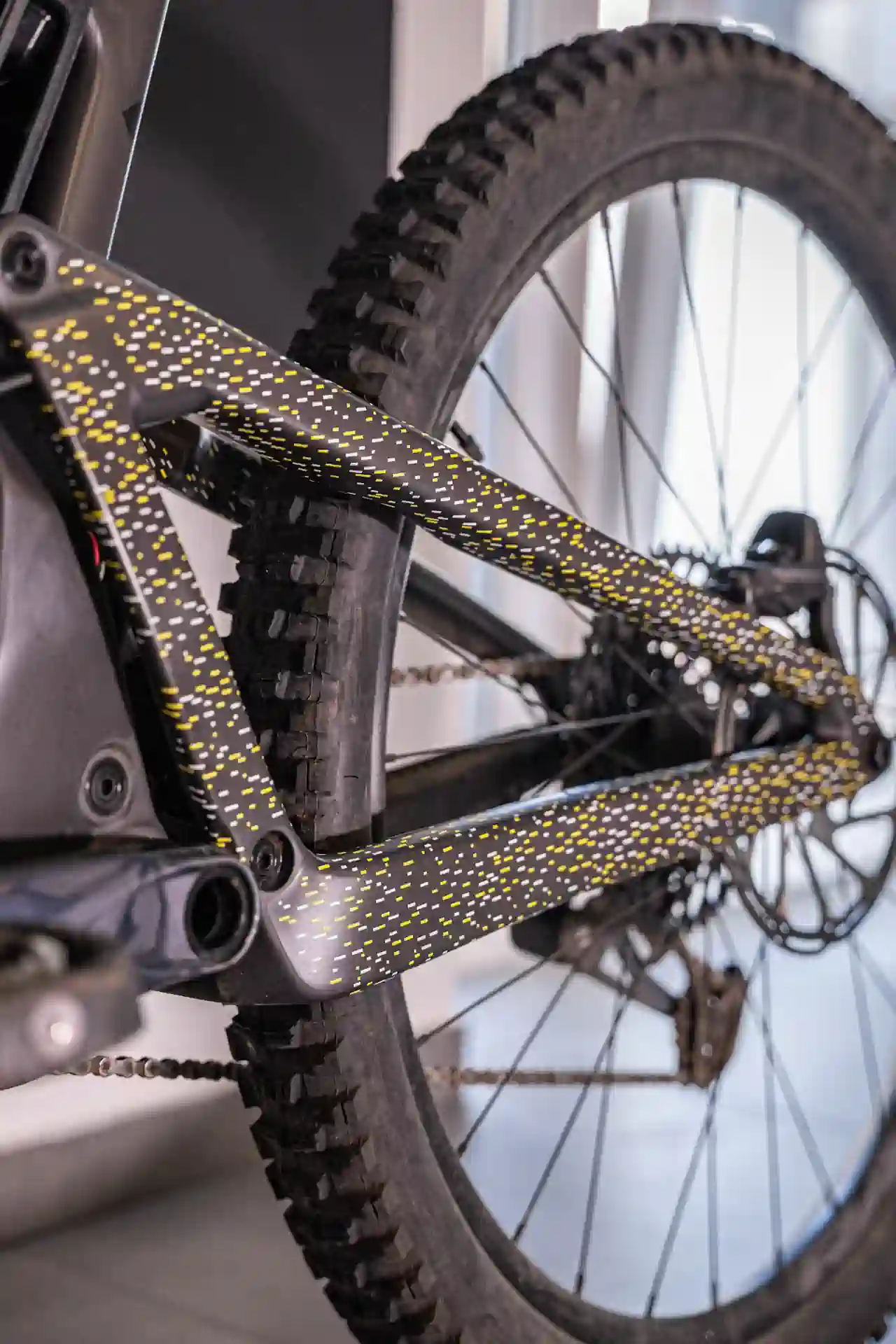 Zbliżenie na tylną część ramy roweru z żółtymi i białymi kropkami na folii ochronnej