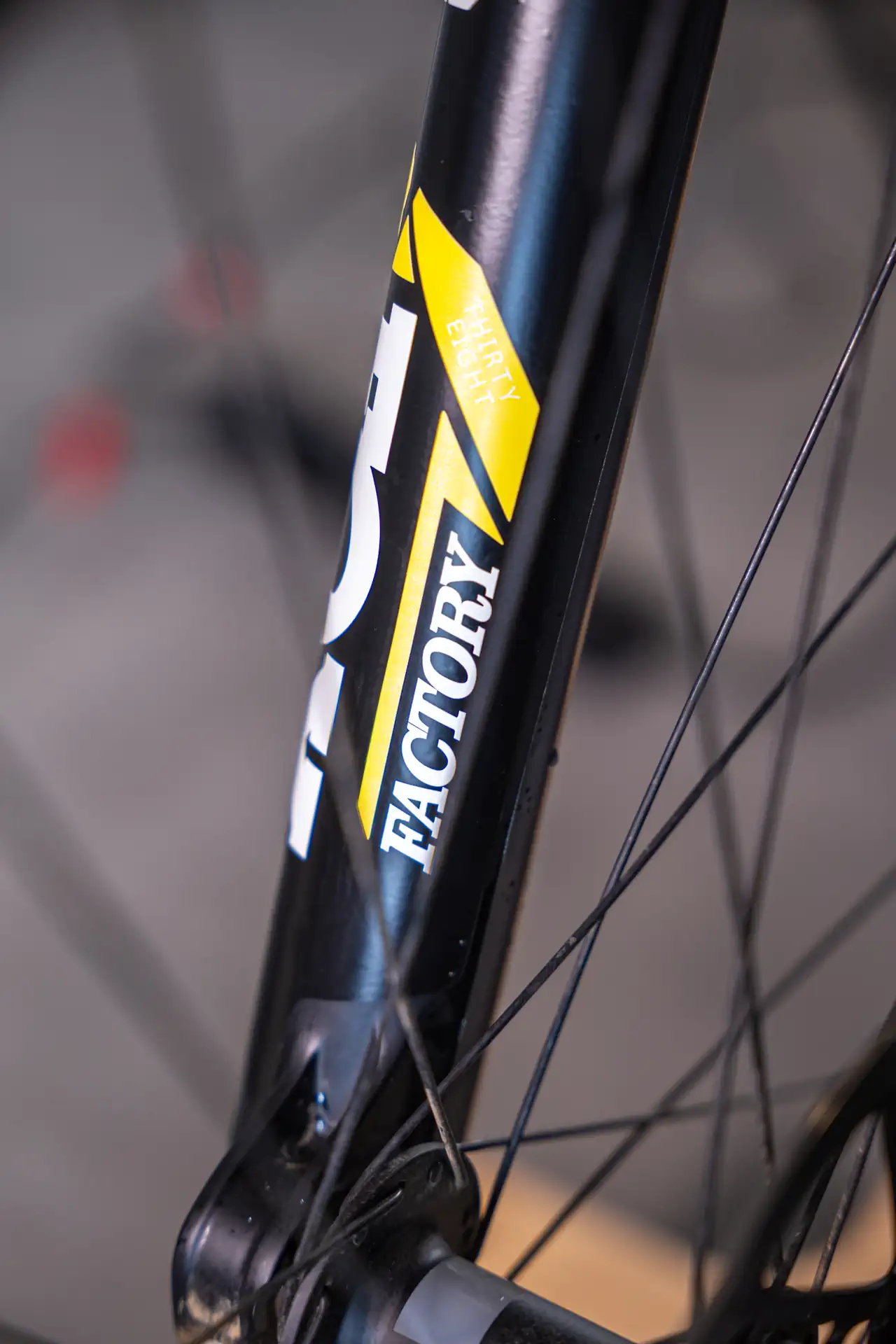 Część przedniego amortyzatora roweru z żółto-czarnym napisem FACTORY