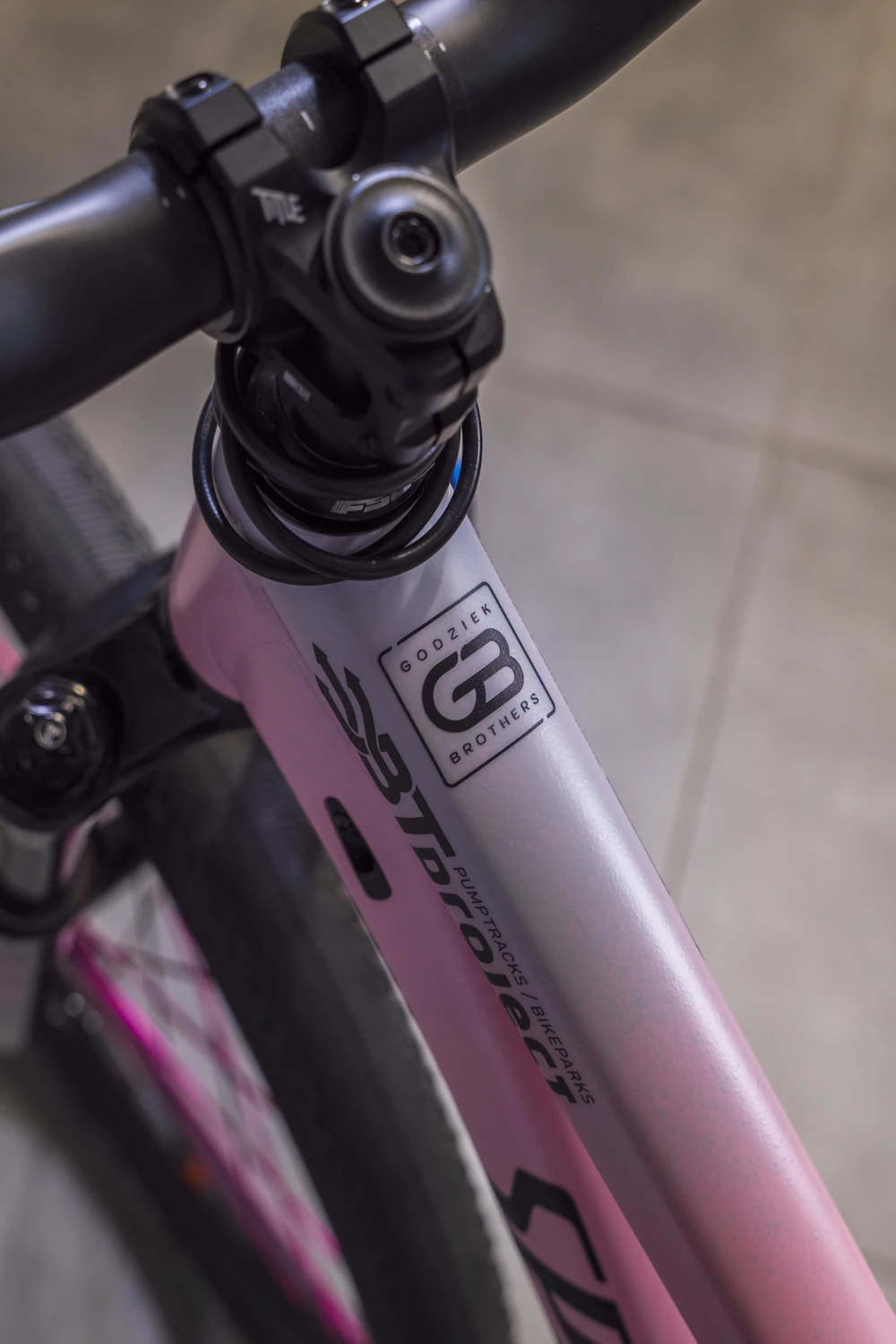 Zbliżenie na górną część różowego roweru z naklejką folii ochronnej i czarnym kierownicą