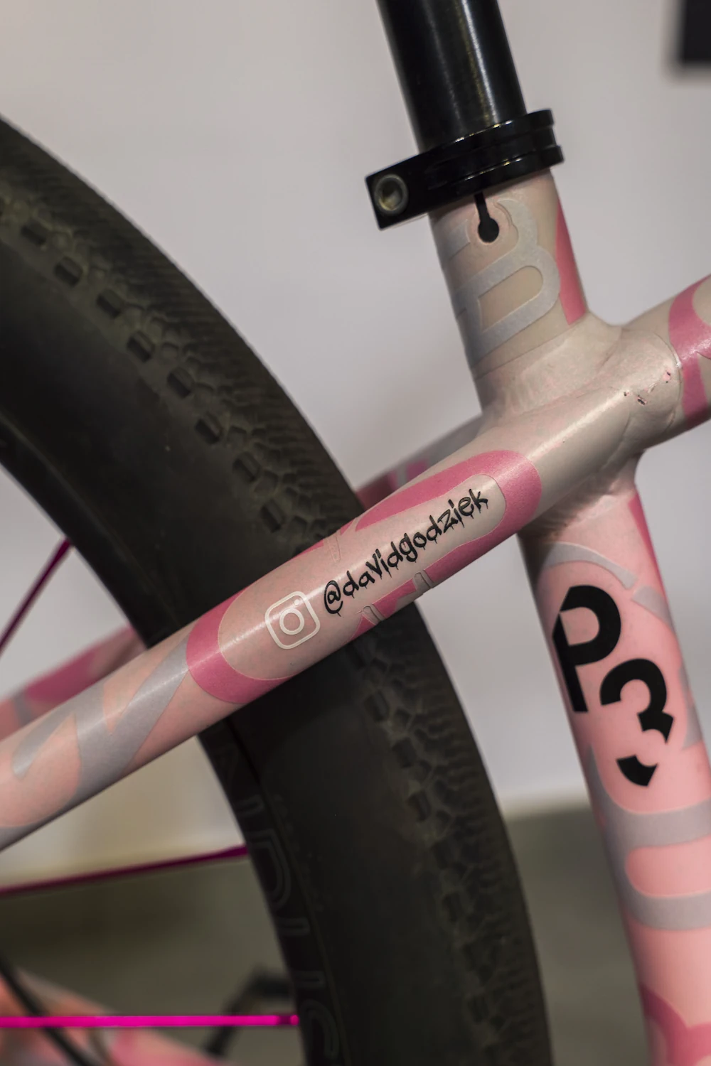 Różowy rower z folią ochronną i oznaczeniami na ramie, widok z boku
