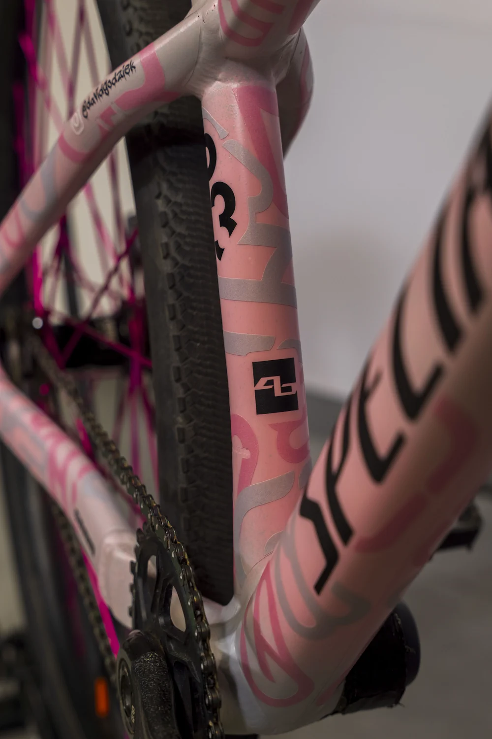 Zbliżenie na ramę różowego roweru z folią ochronną i detalami w odcieniach szarości i różu